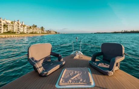 View from the back of a boat in Miami, overlooking calm turquoise waters with coastal buildings in the distance under a clear sky.