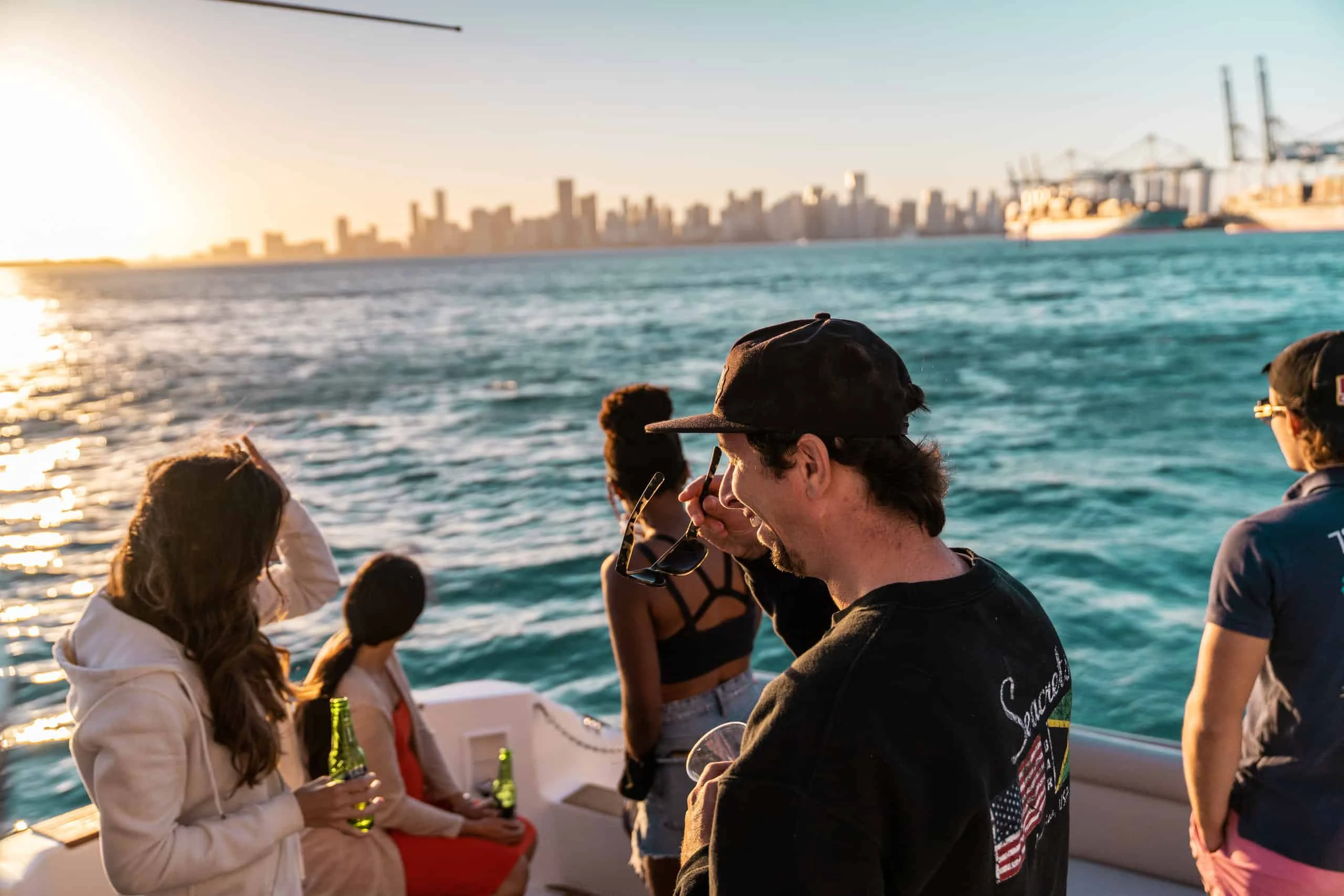 Group of people enjoying a boat ride near the Miami skyline during sunset.