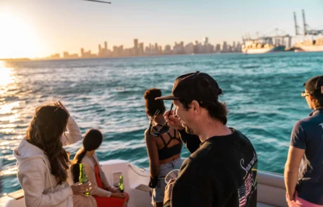 Group of people enjoying a boat ride near the Miami skyline during sunset.