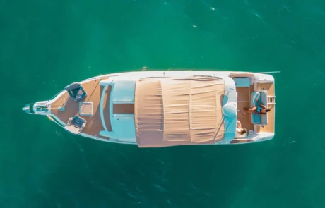 Aerial view of a luxury yacht floating on clear turquoise water off the coast of Miami, featuring a spacious deck with covered and open areas.