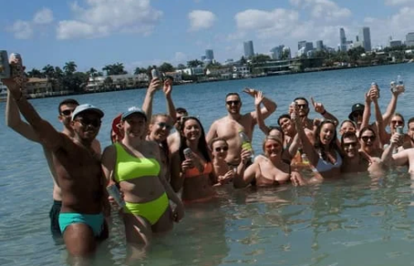 Group of people enjoying a day out in the ocean, posing for a photo with city skyline in the background.