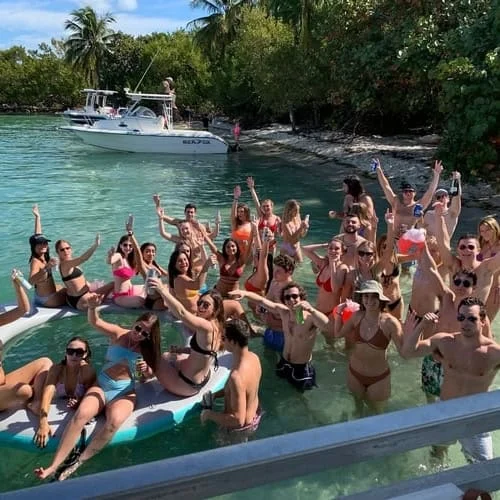 Large group of friends enjoying a social shared boat tour in Miami with Aqua Party Boats, featuring a sandbar party with drinks and music